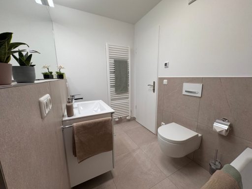 Bad nachher Heller, moderner Badezimmer mit Waschbecken, Toilette und Handtuchhalter.