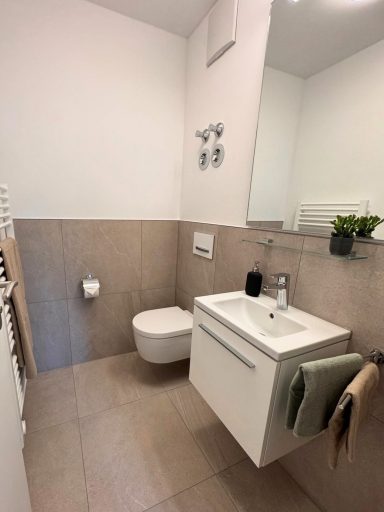 Gäste-WC nachher Gäste-WC renoviert mit hellbraunen Fliesen, Handtuchheizkörper und modernem Waschbecken