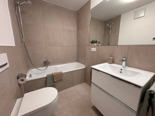 Bad nachher Modernes Badezimmer mit Badewanne, Waschbecken und WC in heller, neutraler Farbgestaltung.