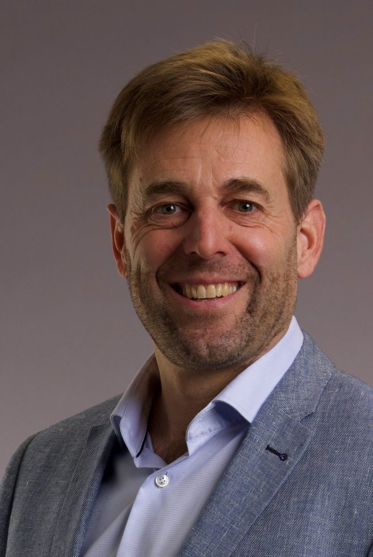Portrait Bernhard Spitz Lächelnder Mann, Inhaber der Spitz Handwerk GmbH, mit blonden Haaren, Trägersakko und Hemd vor neutralem Hintergrund.