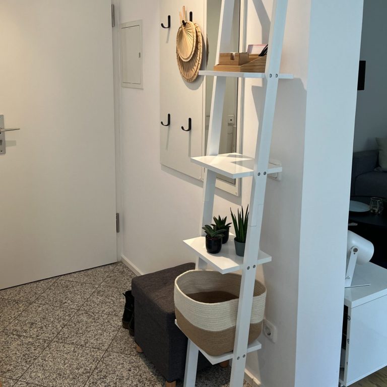 Eingang_nachher Moderne Fluransicht mit weißem Regal, Pflanzen, Spiegel und Wandhaken.